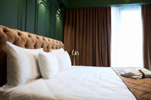 a bedroom with a bed with white pillows and a window at HOTEL VIENA in Satu Mare