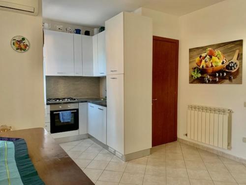 una cocina con armarios blancos y un bol de fruta en la pared en Edera, en Porto Corsini