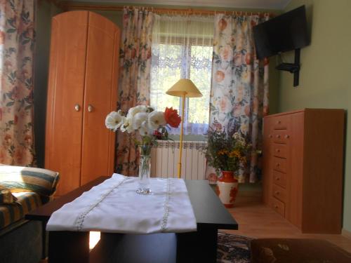 una sala de estar con una mesa con un jarrón de flores. en Domowe Zacisze w Nickulinie en Rajcza