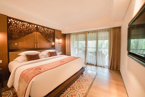 a bedroom with a large bed and a large window at Ramayana Suites and Resort in Kuta