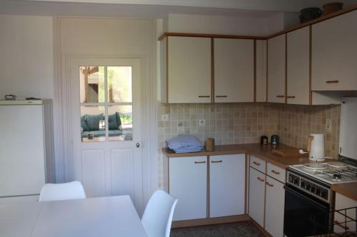 uma cozinha com armários brancos e um forno com placa de fogão em La Buissonnière em Arnay-le-Duc
