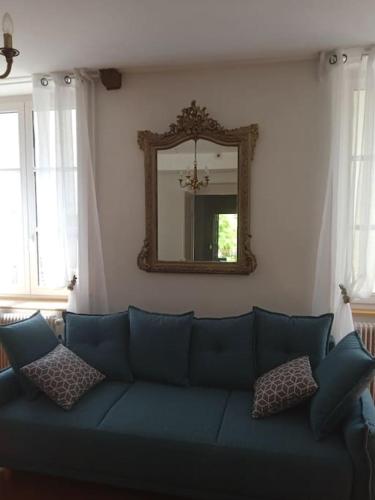 a blue couch in a living room with a mirror at La Buissonnière in Arnay-le-Duc