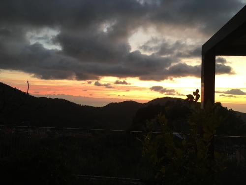 two people sitting on top of a mountain at sunset at Luxury Easy Living in Framura in Framura
