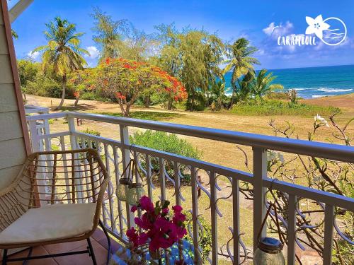 uma varanda com uma cadeira e vista para a praia em STUDIO CARAMBOLE VUE MER - Piscines - Plages - Village vacances Sainte Anne Guadeloupe em Sainte-Anne