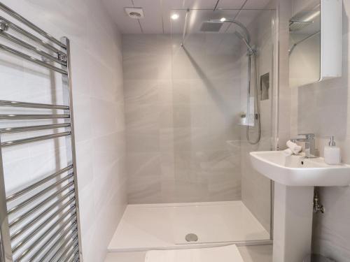 een witte badkamer met een douche en een wastafel bij Hoot Cottage in Keighley