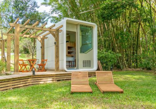 a tiny house with two chairs and a pergola at Nômades Adventure Hostel & Coworking in Florianópolis