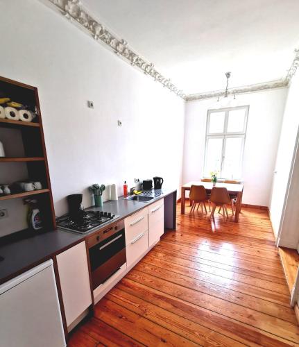 柏林的住宿－Unterkunft Berlin Prenzlauer Berg，厨房铺有木地板,配有白色橱柜。