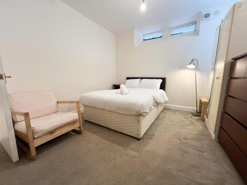 ein Schlafzimmer mit einem Bett und einem Stuhl in der Unterkunft Convenient 2BR Basement Flat in Leith in Edinburgh