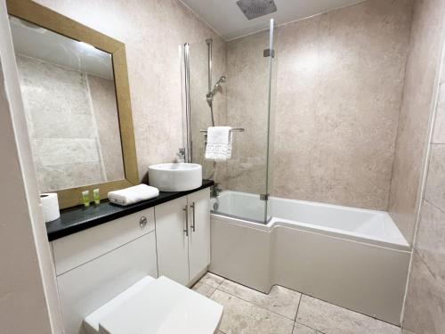 ein Bad mit einer Badewanne, einem Waschbecken und einer Dusche in der Unterkunft Convenient 2BR Basement Flat in Leith in Edinburgh