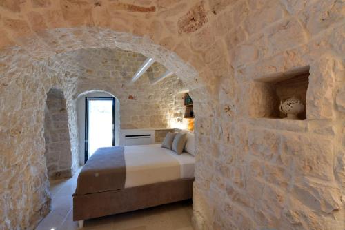 a bedroom with a bed in a stone wall at Trulli di Titti - Luxury Country House in Castellana Grotte