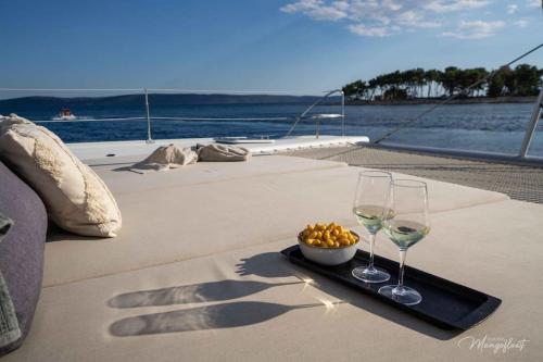 a tray with two wine glasses and a bowl of food at LUXE Crewed Catamaran, Sailing Mangofloat, Croatia in Split