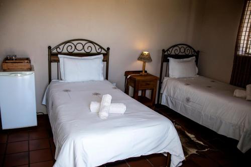 a bedroom with two beds with white sheets and towels at The Vale Karoo Farm in Nelspoort