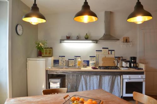 - une cuisine avec un comptoir, un réfrigérateur et une table dans l'établissement les gîtes du passage: le perchoir, à Passenans