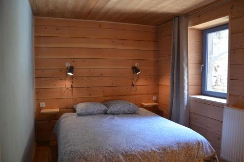 een slaapkamer met een bed in een houten muur bij les gîtes du passage: le perchoir in Passenans