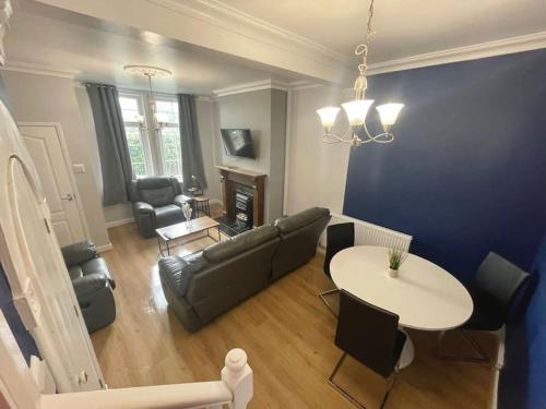 uma sala de estar com um sofá, uma mesa e cadeiras em House near city centre em Hull