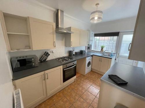 uma cozinha com armários brancos e bancadas pretas em House near city centre em Hull
