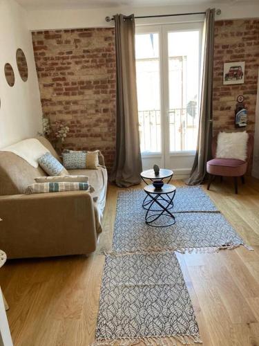 un salon avec un canapé et un mur de briques dans l'établissement Nid douillet Trouville sur mer, à Trouville-sur-Mer