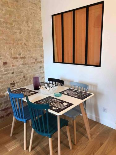 - une table à manger avec 4 chaises bleues dans l'établissement Nid douillet Trouville sur mer, à Trouville-sur-Mer