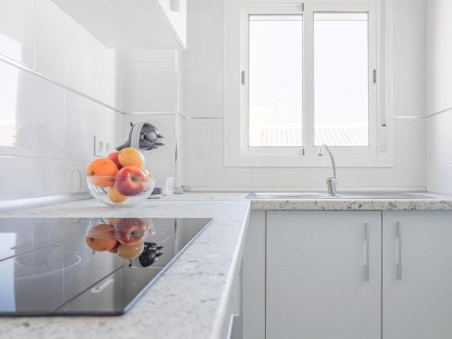 a white kitchen with a bowl of fruit on a counter at Algaba Severo Ochoa 1 in La Algaba