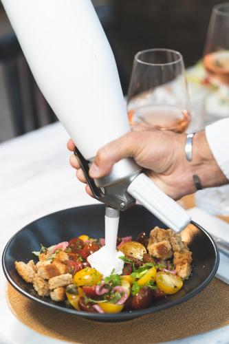 a person holding a spatula over a plate of food at Zeus Village Resort - Adults Only in Kato Daratso