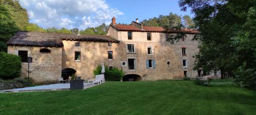 にあるLe gîte du moulin au fil de l eauの緑の庭のある大きな石造りの建物