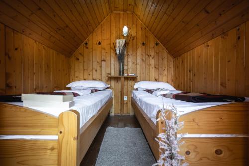 two twin beds in a wooden room with at Dolphin Camping in Sfântu Gheorghe