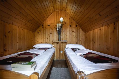 a room with two beds in a wooden cabin at Dolphin Camping in Sfântu Gheorghe