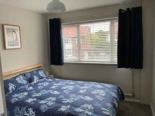 a bedroom with a blue bed and a window at Large 2-bedroom maisonette with free parking in Twickenham