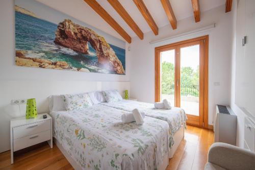 een witte slaapkamer met een bed en een groot raam bij La Forca in Santa Margalida