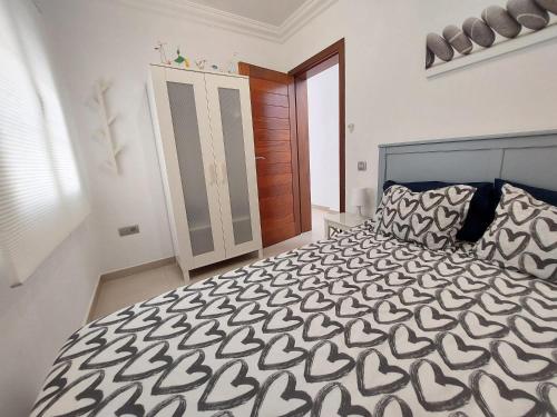 a bedroom with a bed with a black and white comforter at Dunas de Famara in Famara