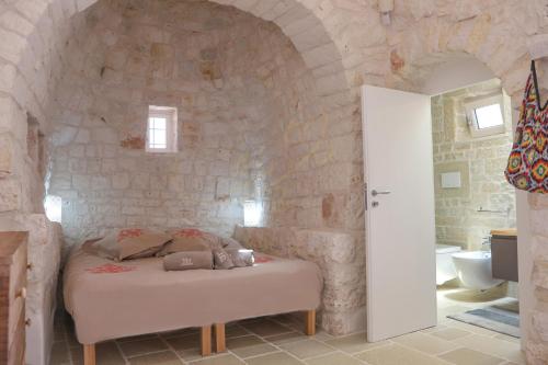 una camera con un letto in una parete in pietra di Trulli&Dimore - TRULLI DELLA MAGNOLIA a Monopoli