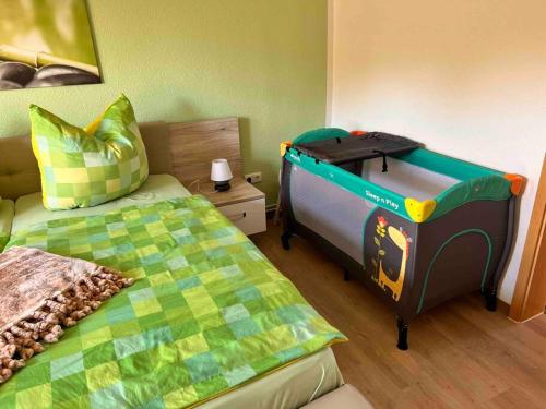 1 dormitorio con 1 cama y 1 cuna de juguete en FeWo Ostsee Oase - gemütlich, ländlich, WLAN en Marlow