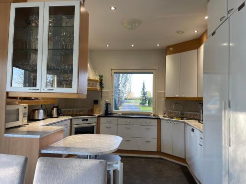 a kitchen with white cabinets and a table and a window at Villa Jokiranta in Eurajoki