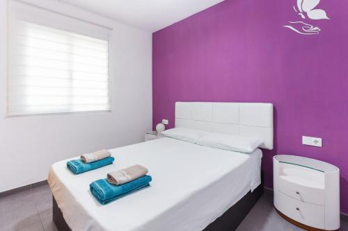ein Schlafzimmer mit einem weißen Bett und einer lila Wand in der Unterkunft Delfines in Xeraco