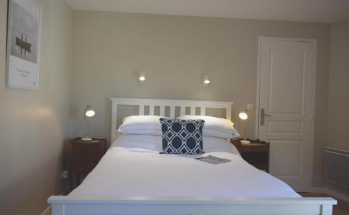 Una cama blanca con dos almohadas encima. en La Maison du Tourniquet, en Aubeterre-sur-Dronne