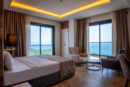 a hotel room with a bed and chairs and windows at CİTY POİNT BEACH&SPA HOTEL in Didim