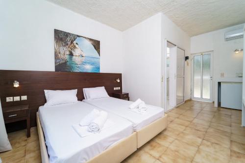 a bedroom with a large bed with white sheets at MaYo Rooms Zakynthos in Akrotiri