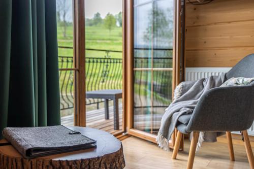 a room with a chair and a table and a balcony at Apartamenty Augustynówka in Brzegi