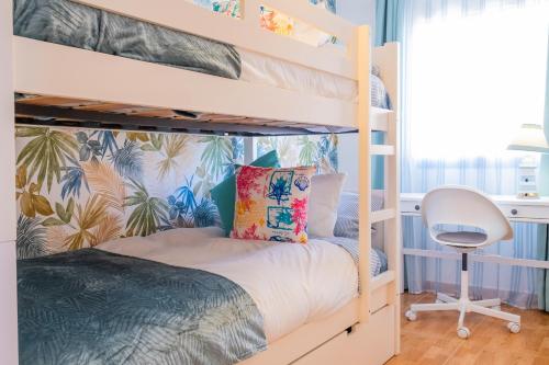 a bedroom with bunk beds with a desk and a chair at ViVaTenerife - Cosy and elegant flat in Los Abrigos in Los Abrigos