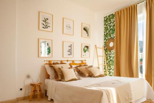 una camera bianca con un letto con cuscini e una finestra di LA CASITA ad Alassio