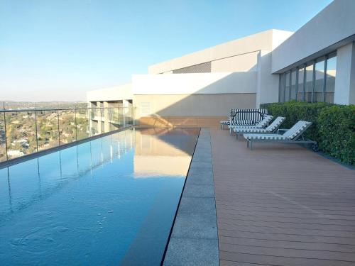 a building with a swimming pool and some chairs at Black Marble - Menlyn Residence Apartments in Pretoria