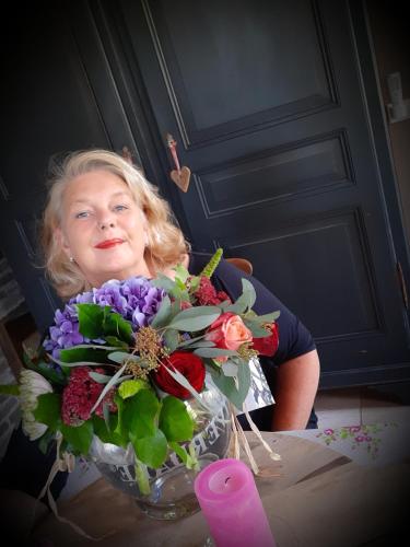 a woman sitting at a table with a vase of flowers at B&B De Verre Kijker in Barsingerhorn