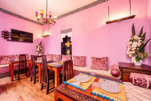ein Wohnzimmer mit rosa Wänden, einem Tisch und Stühlen in der Unterkunft Riad Sidi Mimoune & Spa in Marrakesch