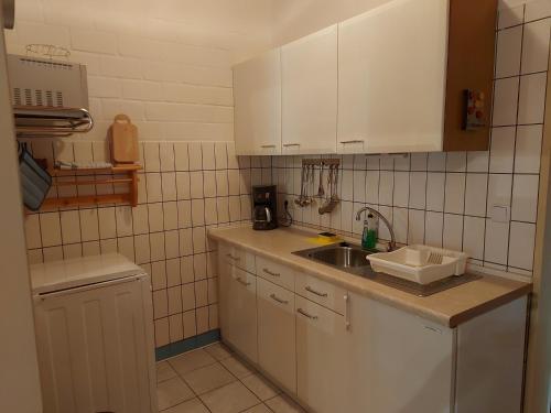 a small kitchen with white cabinets and a sink at Appartement Sandwater in Ihlow