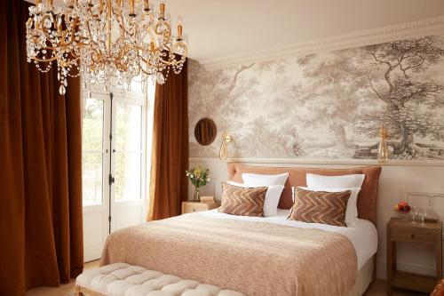 a bedroom with a large bed and a chandelier at Château Léognan, Domaine viticole - proche Bordeaux in Léognan