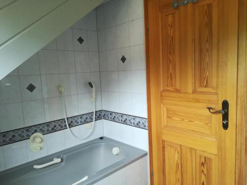 a bathroom with a bath tub next to a wooden door at Ferienwohnung Hopfengärtner in Hiltpoltstein