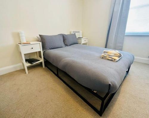 uma cama num quarto com uma mesa-de-cabeceira e uma cama sidx sidx em Studio apartment, The Suffolks. em Cheltenham