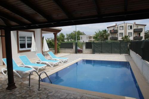 - une piscine avec 2 chaises et un parasol dans l'établissement Villa, à Belek