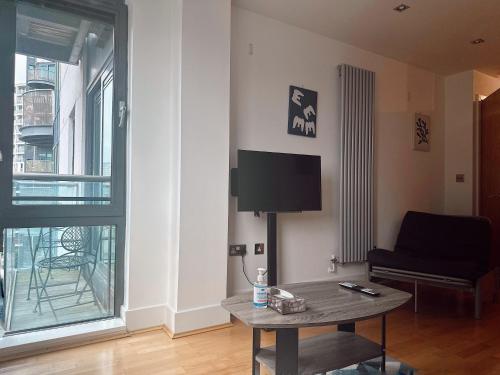 a living room with a table and a tv and a couch at Canary Wharf - Luxury Apartments in London