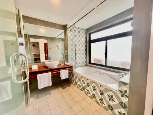 a bathroom with a tub and a sink and a window at DACO Hotel in Siem Reap